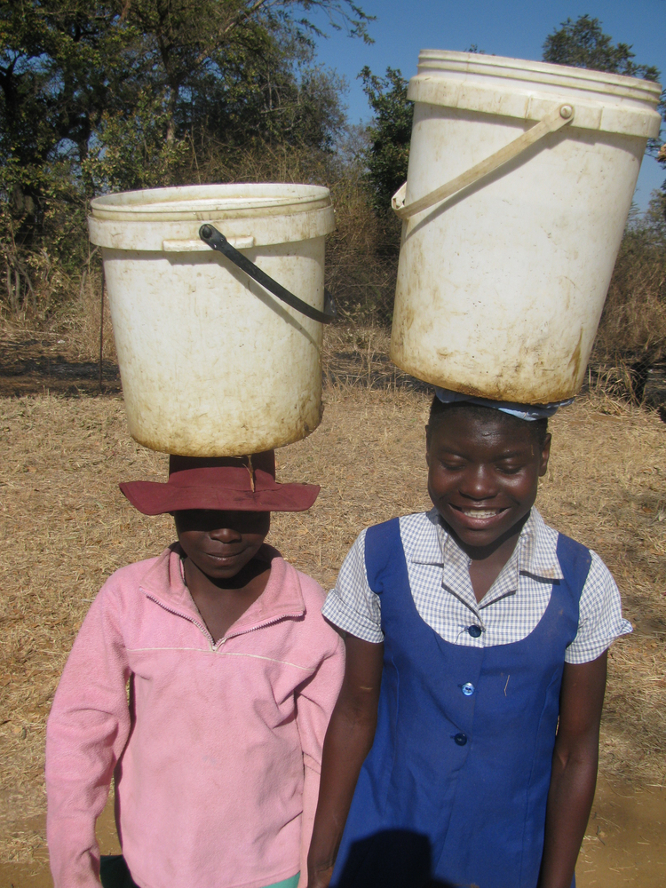 Two young women walk long distances due to the water crisis in Zimbabwe.